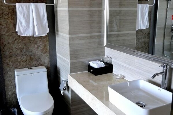 A bathroom with a toilet, sink, mirror, and towel rack.