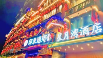 A hotel with multiple balconies, illuminated signage, and a traditional architectural style.