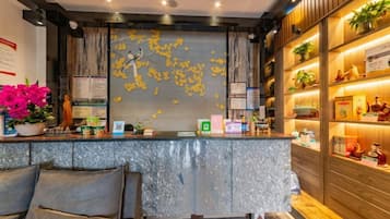 A hotel reception area with a marble counter, seating area, and a wall with decorative elements.