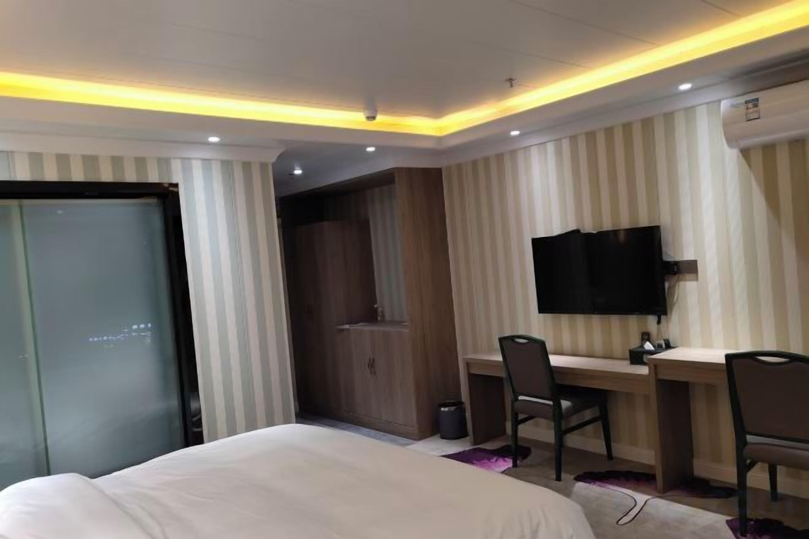 Une chambre d’hôtel comprenant un lit, un bureau, une chaise, une télévision et une armoire.