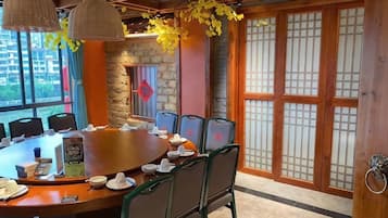 A conference room with a round table, chairs, and a wooden door with traditional design.