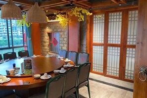 A conference room with a round table, chairs, and a wooden door with traditional design. - Xingyuewan Hotel (Lianzhou)
