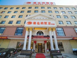 A hotel with a traditional architectural style, featuring a central entrance with columns, a red carpet, and a signboard.