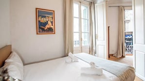 Une chambre d’hôtel avec un lit, une affiche de Cannes et une vue sur le balcon extérieur.