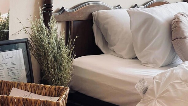 Una cama bien hecha con sábanas blancas y un cabecero de madera oscura.