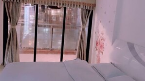 A hotel room with a large bed, a window with curtains, and a view of the outside. - Free Space Youth Hostel (Zhanjiang)