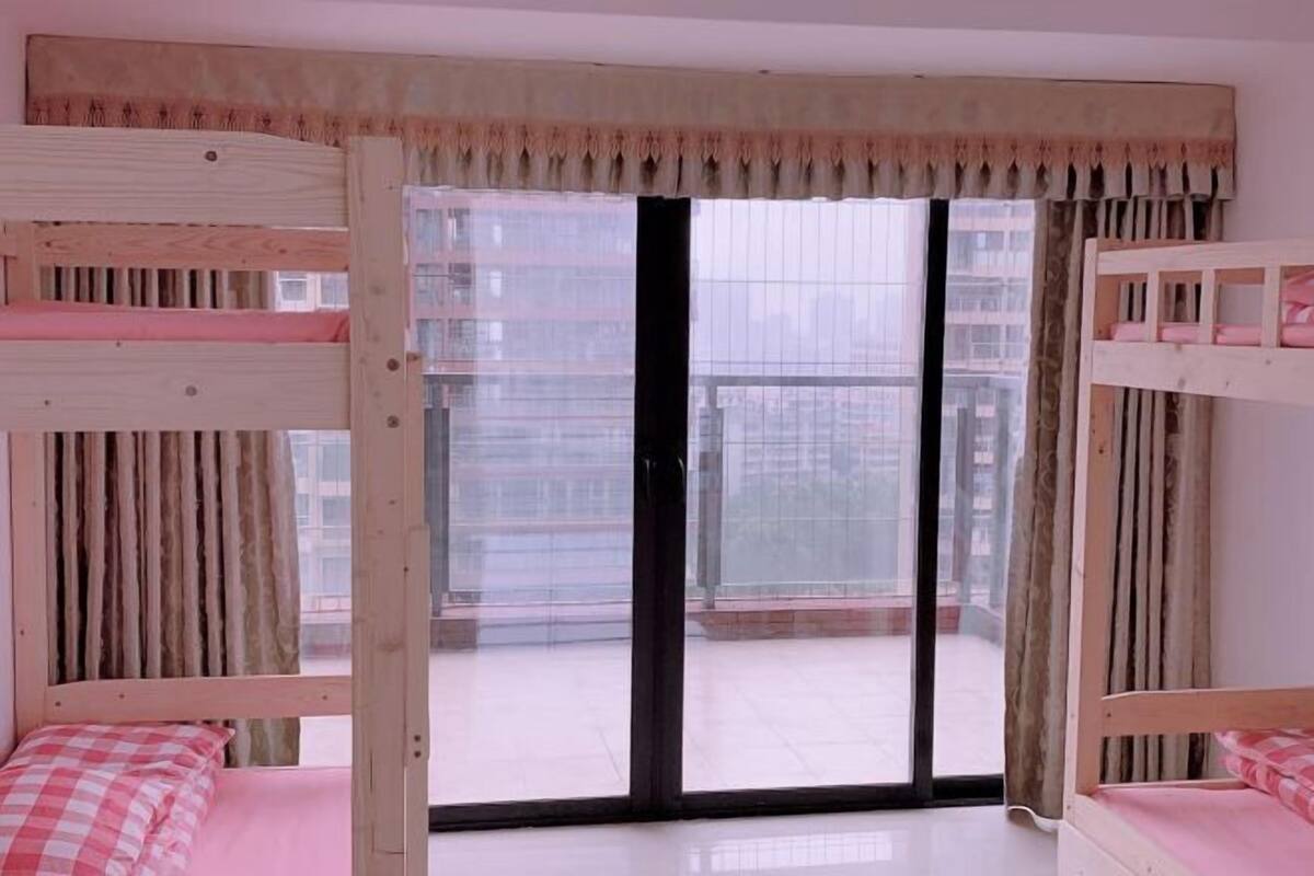 A room with a bunk bed, a sliding glass door to a balcony, and a checkered bedspread.