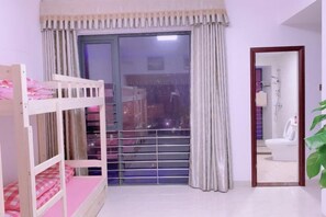 A bedroom with a bunk bed, a large window with curtains, and a bathroom visible through an open door. - Free Space Youth Hostel (Zhanjiang)