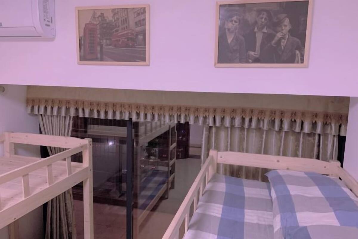 A room with bunk beds, a window with curtains, and framed pictures on the wall.