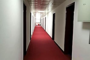 A long, narrow hallway with a red carpet, doors on both sides, and a light fixture on the ceiling. - Jinsixia Guobin Grand Hotel (Ludumen) (Shangnan)