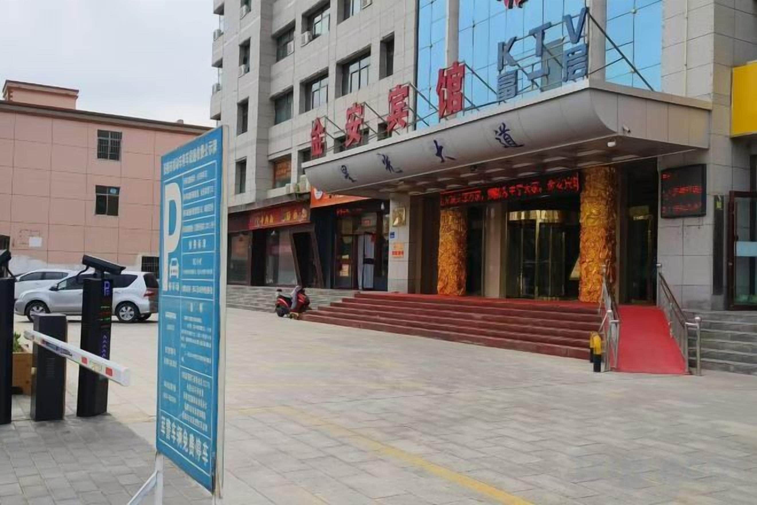 A hotel entrance with a red carpet, a signboard, and a staircase leading to the entrance.