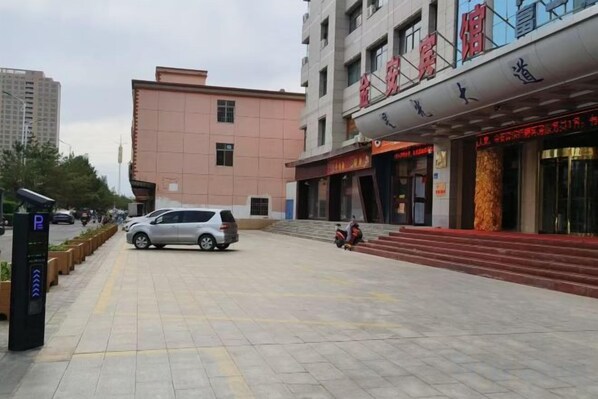 Un bâtiment avec une enseigne rouge, un espace de stationnement et une voiture garée devant.