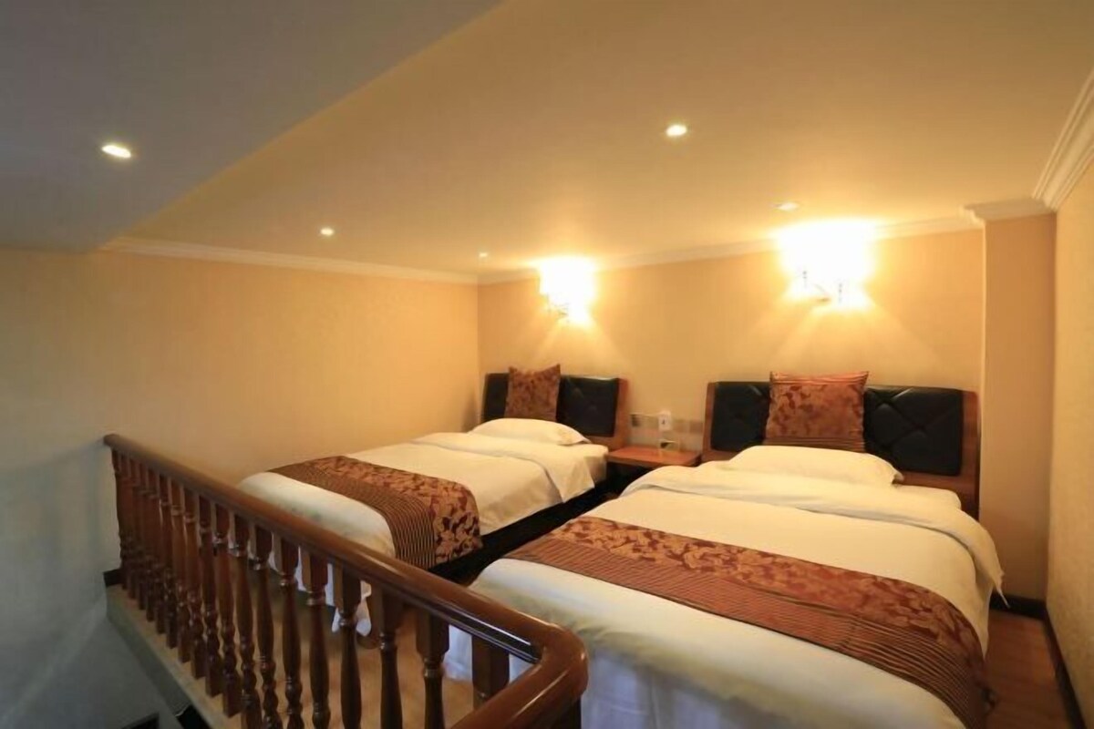 A hotel room with two beds, a wooden staircase, and wall-mounted lighting.