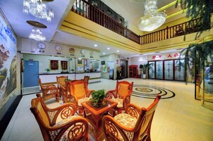 Un vestíbulo de hotel con mostrador de recepción, zona de estar y una escalera.