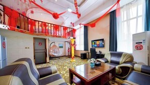 A hotel lobby with a sofa, a coffee table, a TV, and a staircase. - Jin'an Hotel (Zhangye)