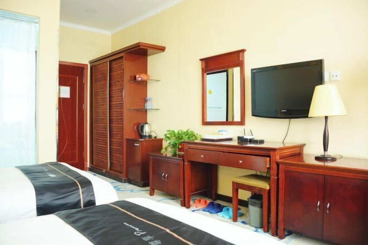 A hotel room with two beds, a desk, a television, and a wardrobe.
