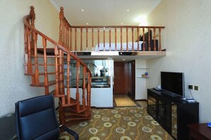 A room with a wooden staircase, a bed on the upper level, a television, and a desk. - Jin'an Hotel (Zhangye)