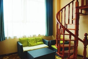 Una habitación con un sofá, una mesita y una escalera de madera.