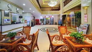 A hotel lobby with wooden furniture, a central circular design on the floor, and a reception area with a clock and a sign. - Jin'an Hotel (Zhangye)