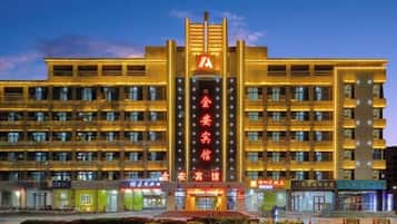 A hotel with a prominent vertical sign, multiple floors, and a well-lit facade.