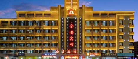 A hotel with a prominent vertical sign, multiple floors, and a well-lit facade.