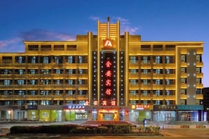 Un hotel con un letrero vertical llamativo, varios pisos y una fachada bien iluminada.