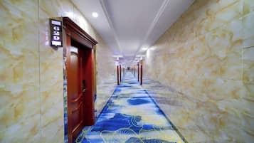 A hallway with marble walls and a patterned carpet, leading to a door with a sign above it.