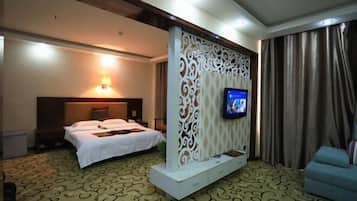 Ein Hotelzimmer mit einem Bett, einem an einer Zierleiste montierten Fernseher, einer Couch und einem gemusterten Teppich.
