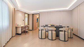 A modern hotel room with a central dining area, a small kitchenette, and a seating arrangement with round stools. - Guanbeiding Hotel (Nan'an)