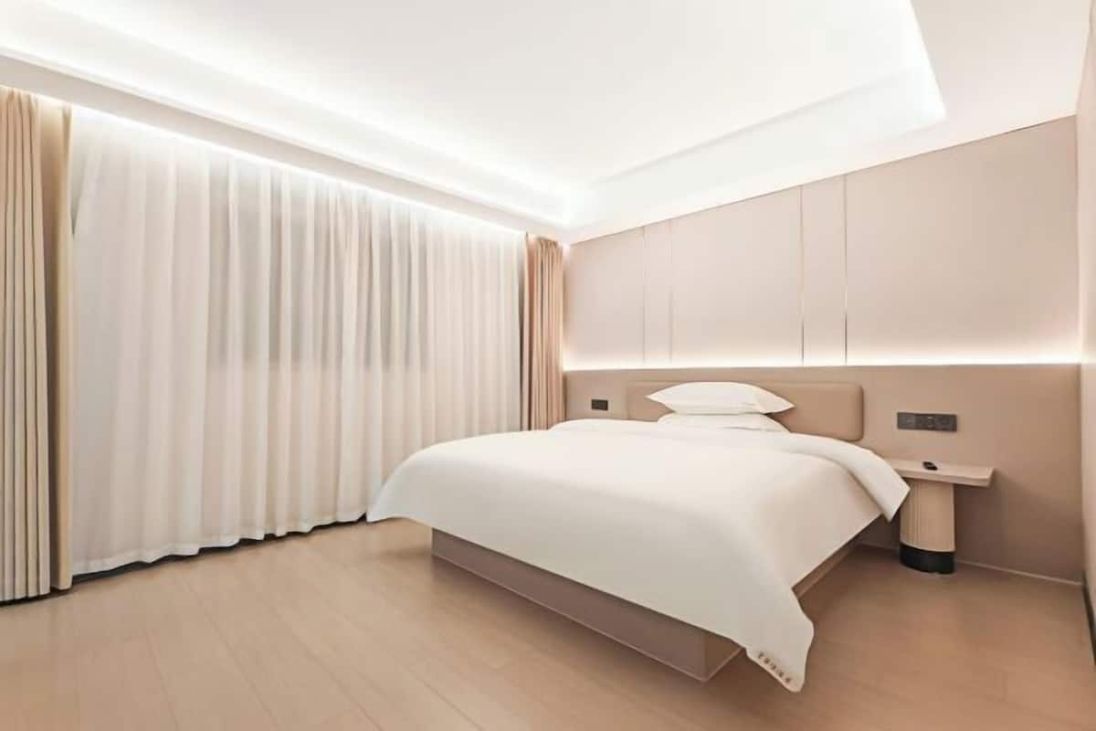 A modern hotel room with a large bed, bedside tables, and a built-in nightstand.