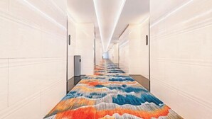 A long, narrow hallway with white walls and a colorful, abstract carpet. - Guanbeiding Hotel (Nan'an)