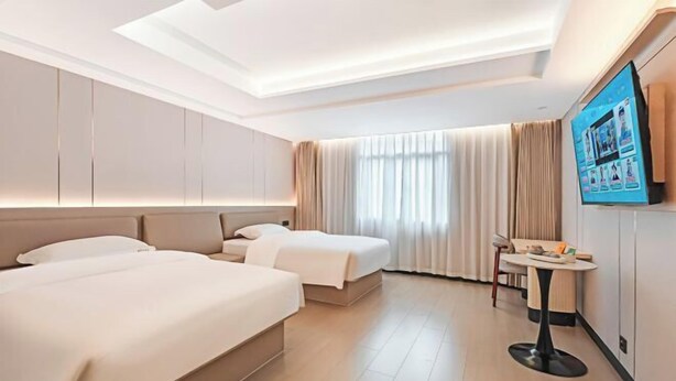 A hotel room with two beds, a TV, a small table, and a window with curtains. - Guanbeiding Hotel (Nan'an)