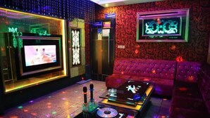 A room with a red sofa, a DJ setup, and a television on the wall. - Guanbeiding Hotel (Nan'an)