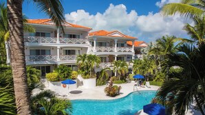 A resort with a swimming pool surrounded by palm trees and multiple balconies.