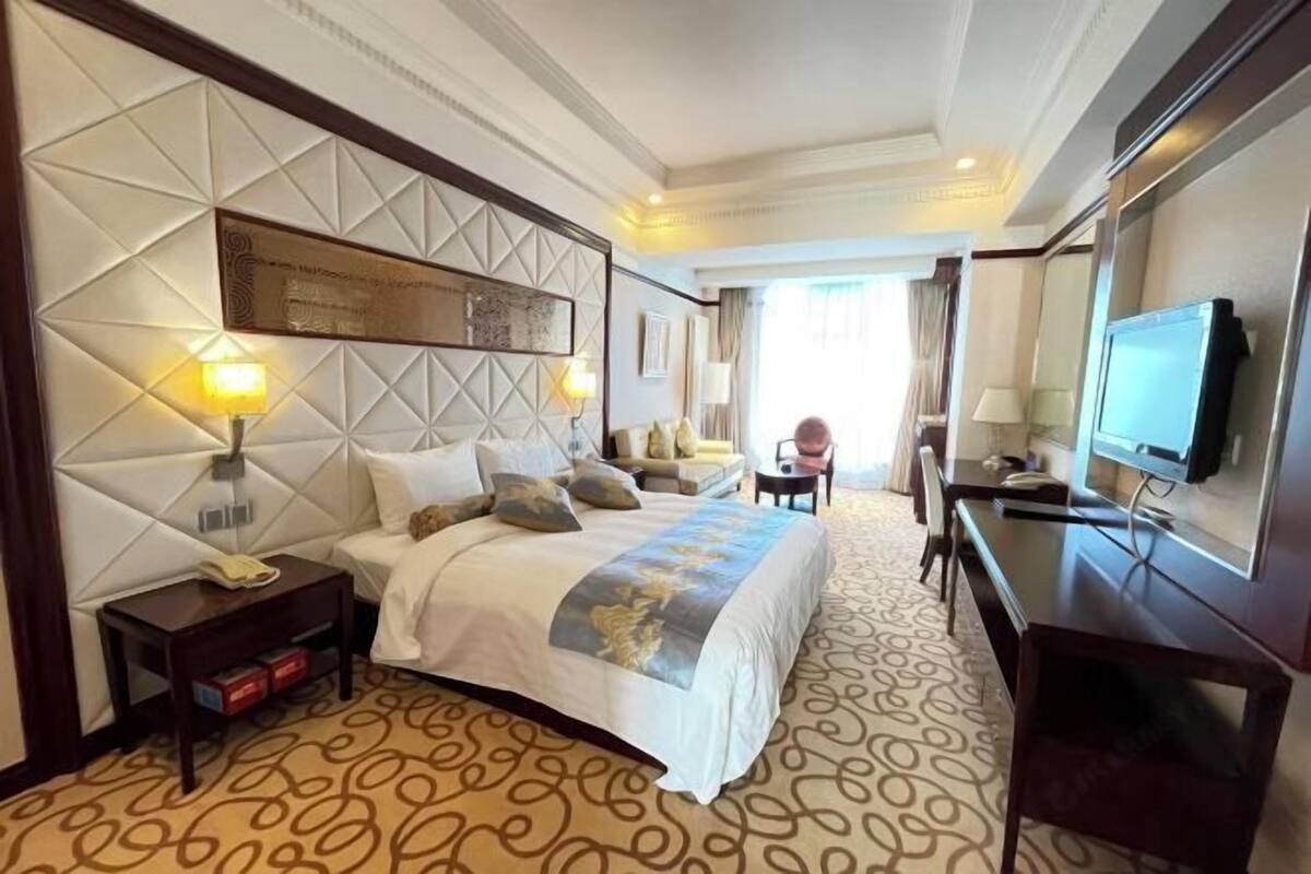 A hotel room with a large bed, a desk, a television, and a view of the outdoors.