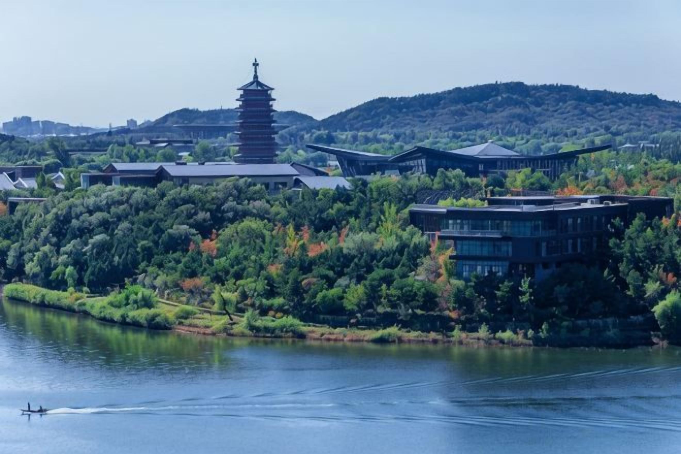 A traditional pagoda-style building surrounded by lush greenery and a body of water.