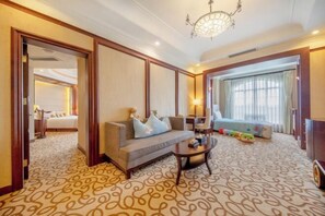 A hotel room with a sofa, a coffee table, a chandelier, a large window with curtains, and a patterned carpet. - Renji Hotel (Beijing)