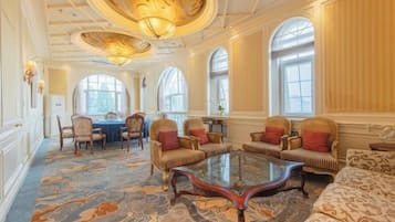 A spacious room with a large round table, several sofas, and a patterned carpet.