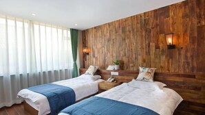 A hotel room with two beds, wooden paneling on the walls, a window with sheer curtains, and a nightstand with a lamp. - Nanxun Kangyu Yashe Inn (Huzhou)