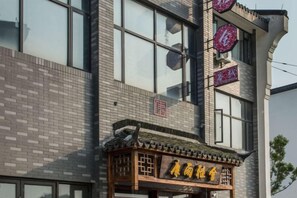 A building with a traditional Chinese architectural style, featuring a tiled roof and a wooden structure with signage.