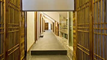 A hallway with a series of doors on either side, leading to a room at the end.