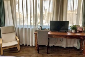 A room with a wooden desk, a chair, a television, and a window with curtains. - Nanxun Kangyu Yashe Inn (Huzhou)