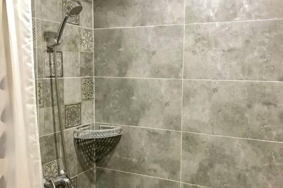 A shower with a handheld showerhead and a wall-mounted faucet.
