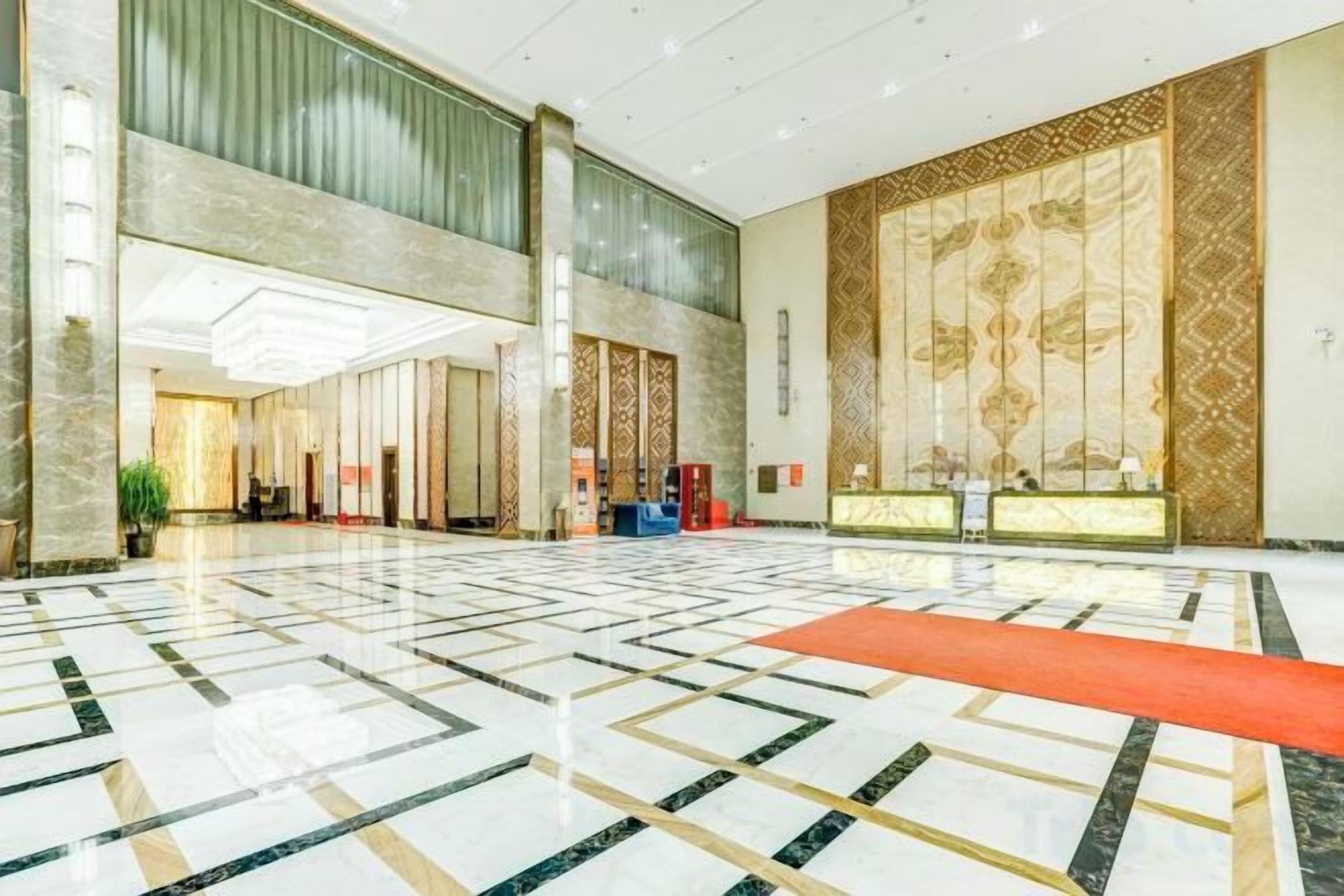 A spacious lobby with a marble floor, a reception desk, and a large decorative wall.