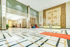A spacious lobby with a marble floor, a reception desk, and a large decorative wall. - Xi Le Hui Hotel (Fujin)