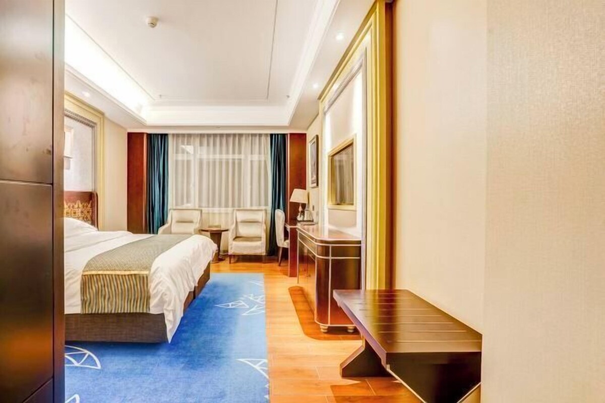 A hotel room with a bed, a desk, a chair, and a television.