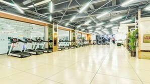 A spacious indoor area with treadmills, a glass wall, and a ceiling with exposed beams and lighting. - Xi Le Hui Hotel (Fujin)