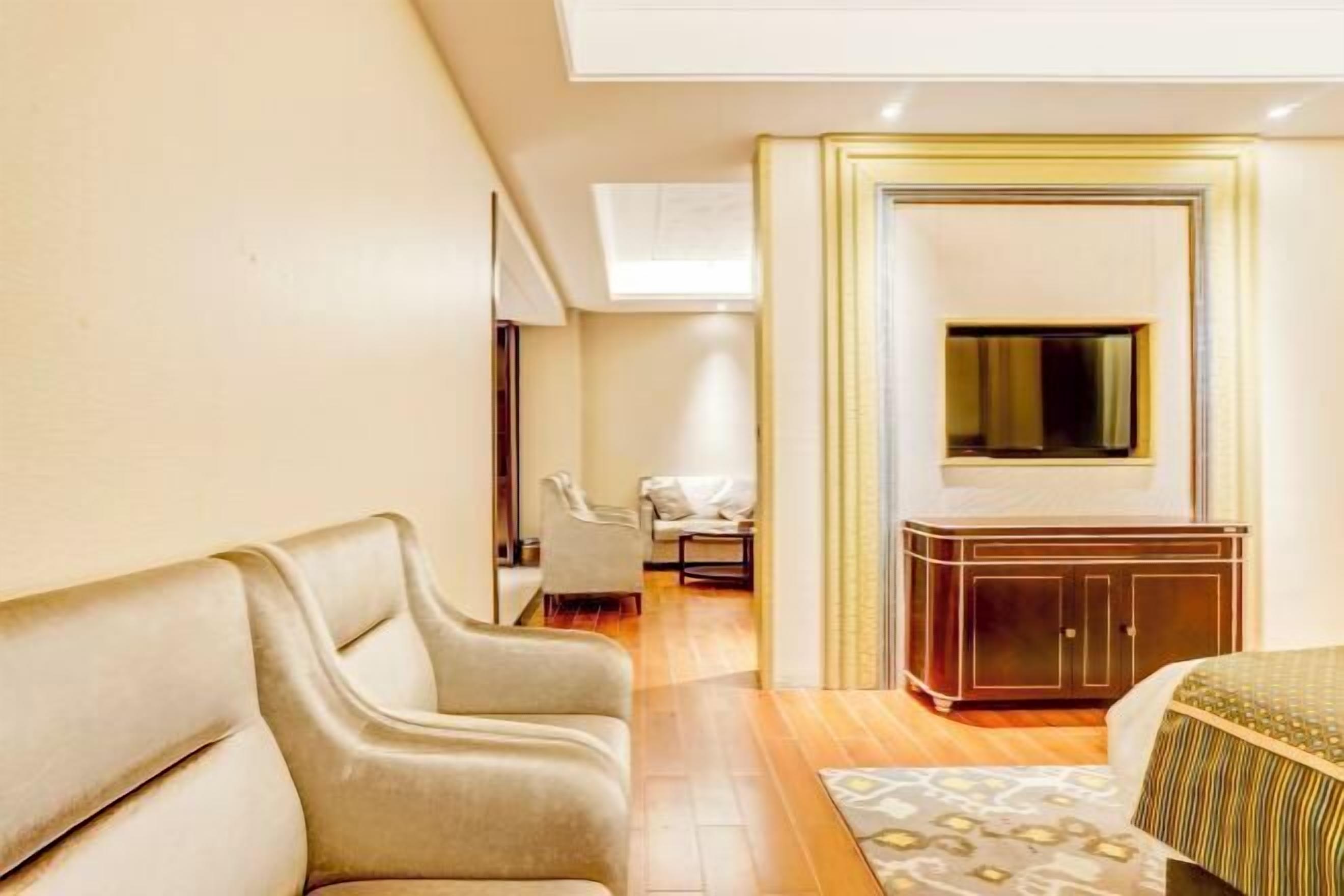 Una habitación de hotel con un sofá, una cama, un armario y un televisor.