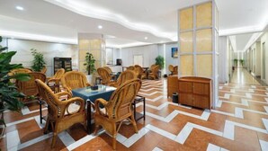 A spacious dining area with wicker chairs and a central table, a hallway with patterned flooring, and a large wooden cabinet. - Shengkai Business Hotel (Chongqing)