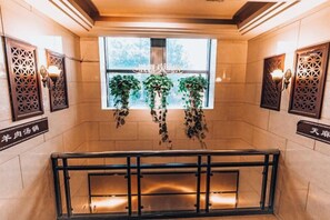 A staircase with a metal railing, a window with hanging plants, and decorative wall sconces. - Shengkai Business Hotel (Chongqing)